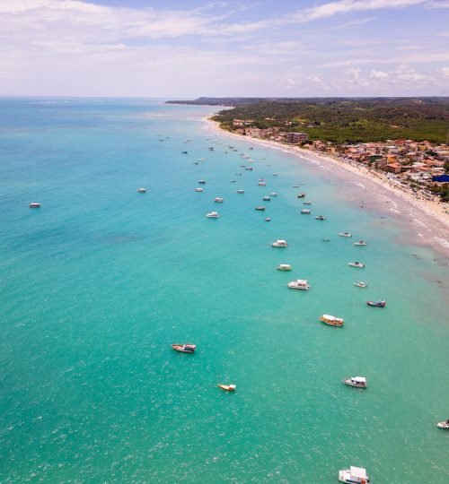 A stunning aerial view of Maragogi beach with turquoise waters and numerous boats.